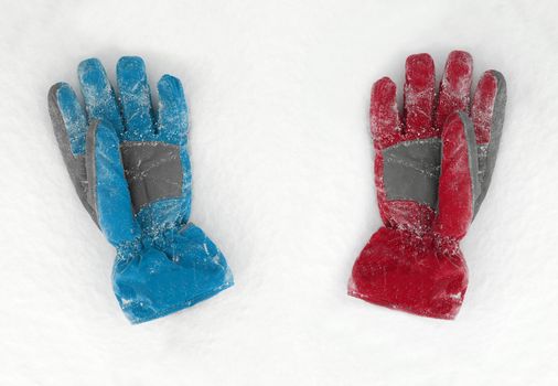 Blue and red gloves lieing on the snow