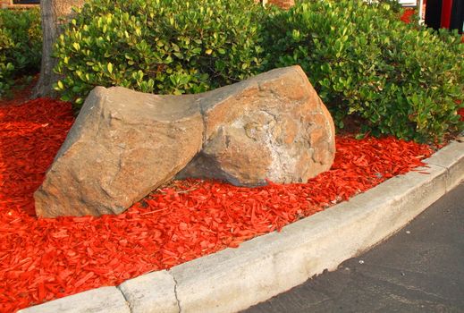 Redwood mulch next to the rocks on a sunny day.