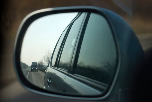 Road in the sideview mirror of a car