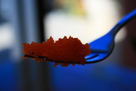 Close up of a salmon caviar on a fork.