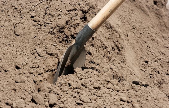 Shovel digging into a pike of soil