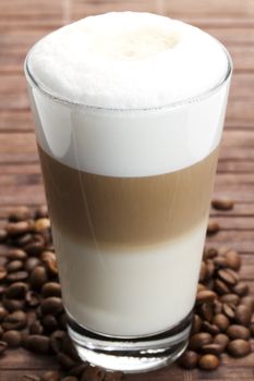 latte macchiato with coffee beans on wooden background