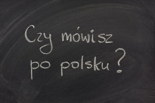 Do you speak Polish question (informal)  handwritten  with white chalk on a blackboard with eraser smudges