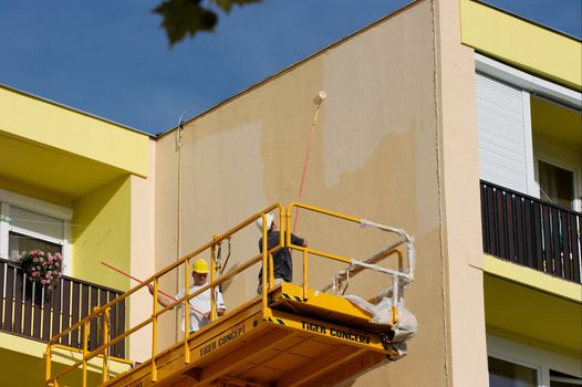 Workers painting in a manlift