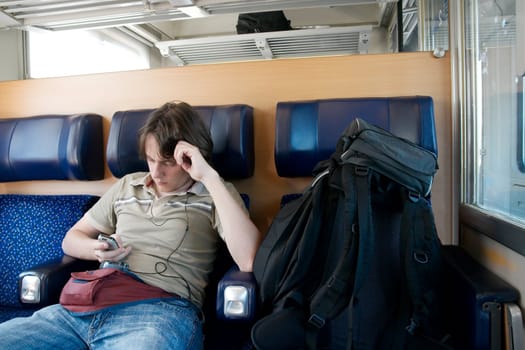 Young man traveling by train with backpack