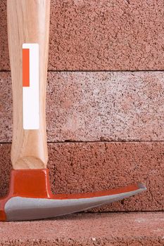 Stonemason's hammer on a background of red bricks.