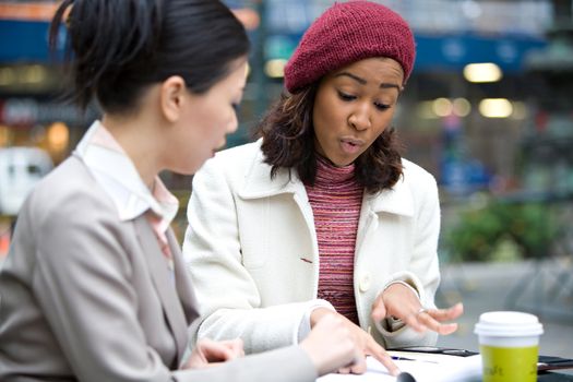 Two business women having a casual meeting or discussion in the city. Shallow depth of field.