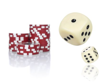 Pair of dice rolling in front of stacked red poker chips.