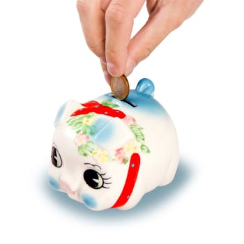 The hand lowering a coin in a pig-coin box