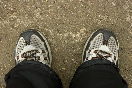 Photo of feet in sports footwear against soil