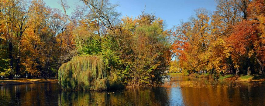 Lazienki park and the lake in fall colors. Walking people faces are not recognizable.
