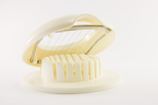 White plastic open egg slicer on a whit background