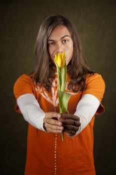 Handsome man reaching out with yellow tulip flower