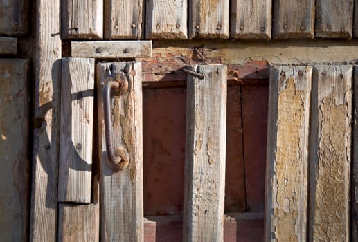 Fragment of an old wooden door with a handle. Close-up, front.