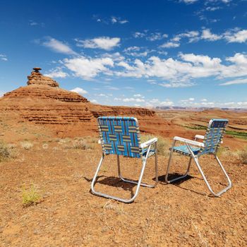 Lawn chairs in scenic desert landscape with mesa land formation.