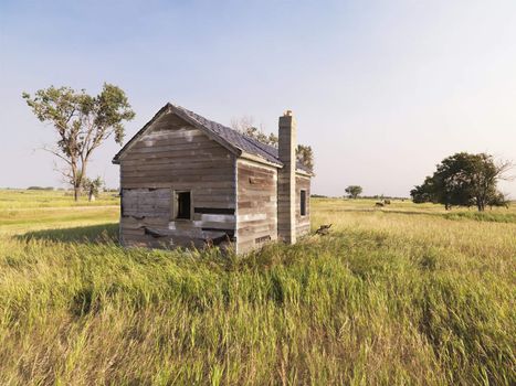 Dilapidated wooden house in rural field.