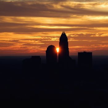 Sunset silhouetting aerial view of Charlotte, North Carolina city skyline.