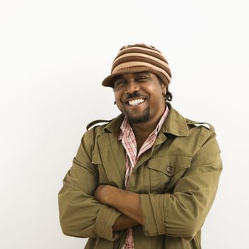 African-American mid-adult man wearing hat and smiling at viewer with arms crossed.