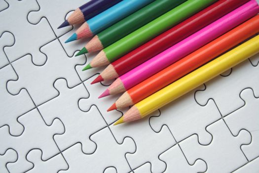 Colorful pencils on a white jigsaw background