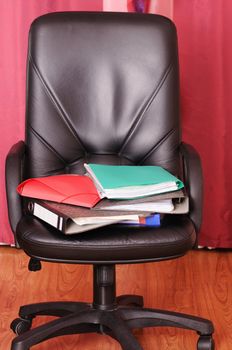 The pile of different documents lays on a black armchair