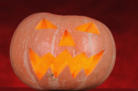 pumpkin with lighting candle inside on red background