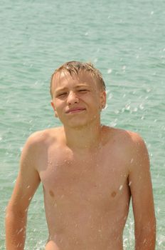 The young man bathes in the sea and creates sparks