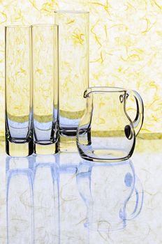 Glass glasses and jug on a yellow background