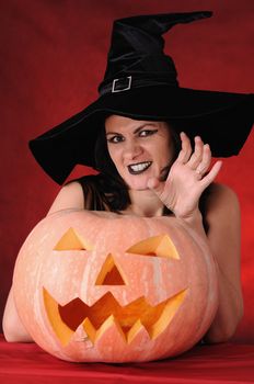 Young witch with a pumpkin on a red background