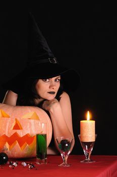 Young witch with a pumpkin on a black  background