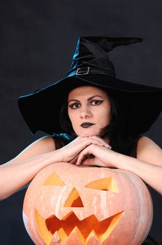 Young witch with a pumpkin on a black  background