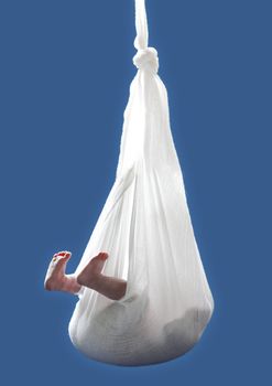 newborn child hanging from cloth over blue background