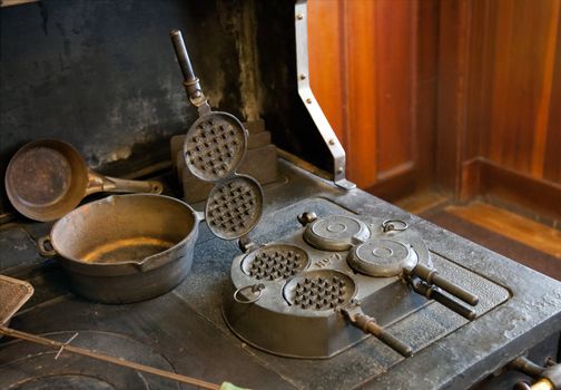Antique farmhouse stove in cast iron with old waffle of pancake maker