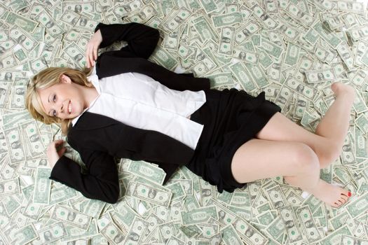Businesswoman laying in money pile