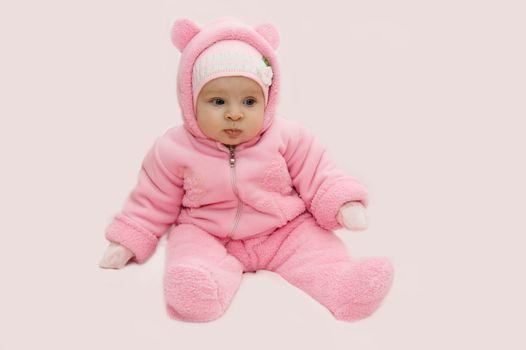 Baby girl in pink snowsuit over pink background