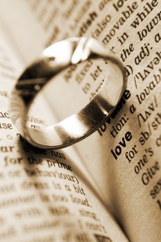 wedding ring near dictionary entry word love in sepia