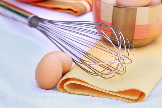 Egg whisk with farm fresh brown eggs. Selective focus with shallow DOF.