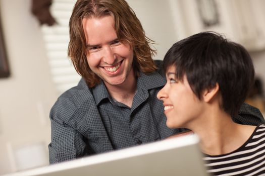 Pretty Smiling Multiethnic Woman and Caucasian Man Using A Laptop Computer Together.