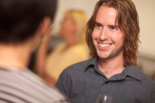 Smiling Young Man with Glass of Wine Socializing in a Party Setting.