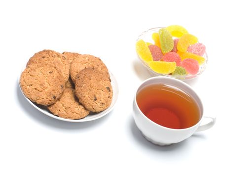 Fruit candy, oats cookies and a cup with tea.