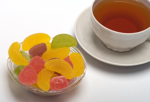 Fruit candy and tea cup. It is isolated on a white background 