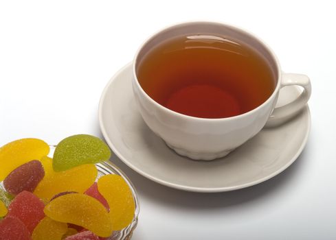 Fruit candy and tea cup. It is isolated on a white background 