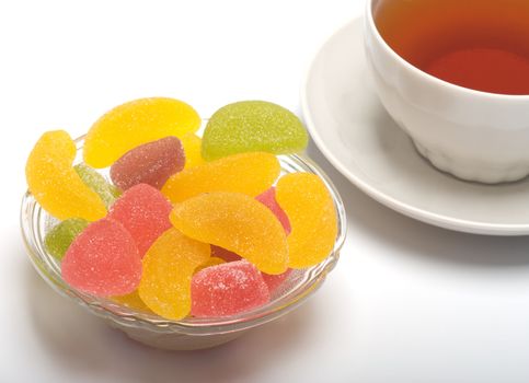 Fruit candy and tea cup. It is isolated on a white background 