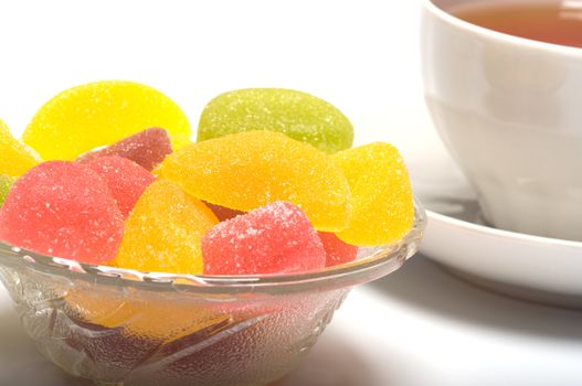 Fruit candy and tea cup. It is isolated on a white background 