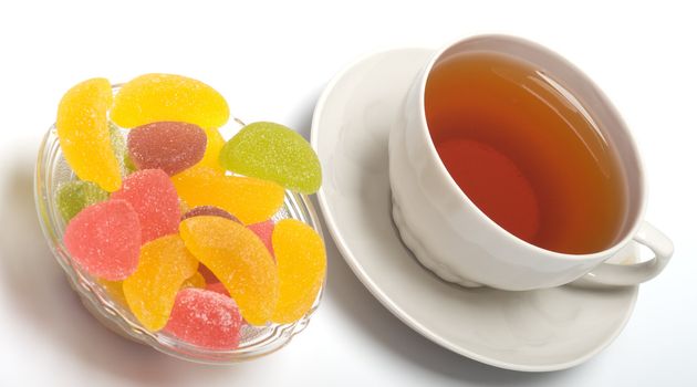 Fruit candy and tea cup. It is isolated on a white background 