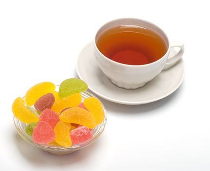 Fruit candy and tea cup. It is isolated on a white background 