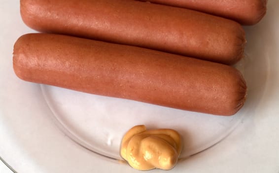 Sausages on a plate with mustard. A close up