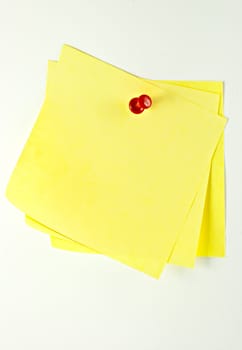 Three yellow sticky paper pinned with a pin at a white background.
