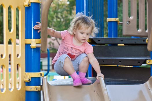 Cute little European toddler girl having fun at the playground in the park.