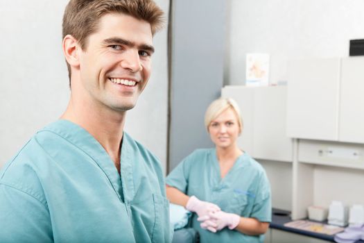 Portrait of male dentist with female assistant standing at dental clinic