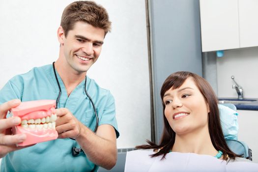 Male dentist explaining a female patient denture work in dental clinic